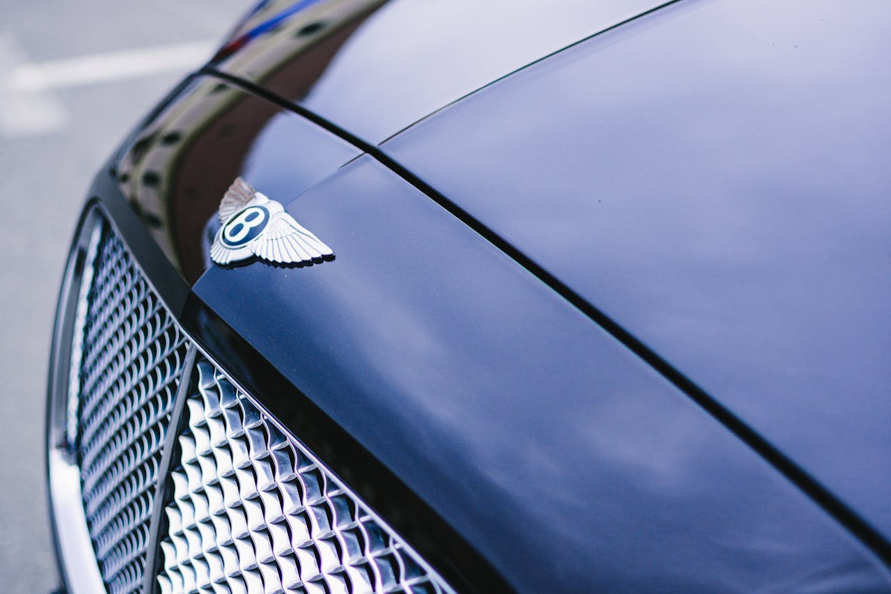Detailed view of a polished luxury car hood with emblem and chrome grille.